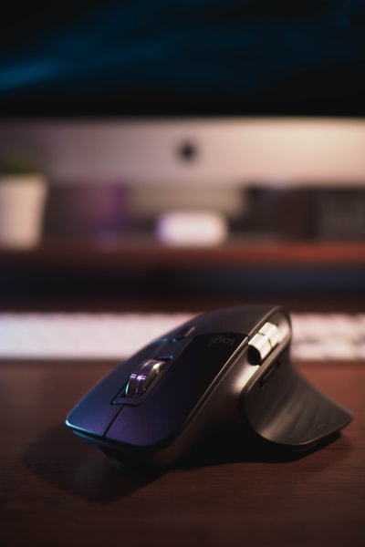 Brown wooden table black wireless computer mouse
